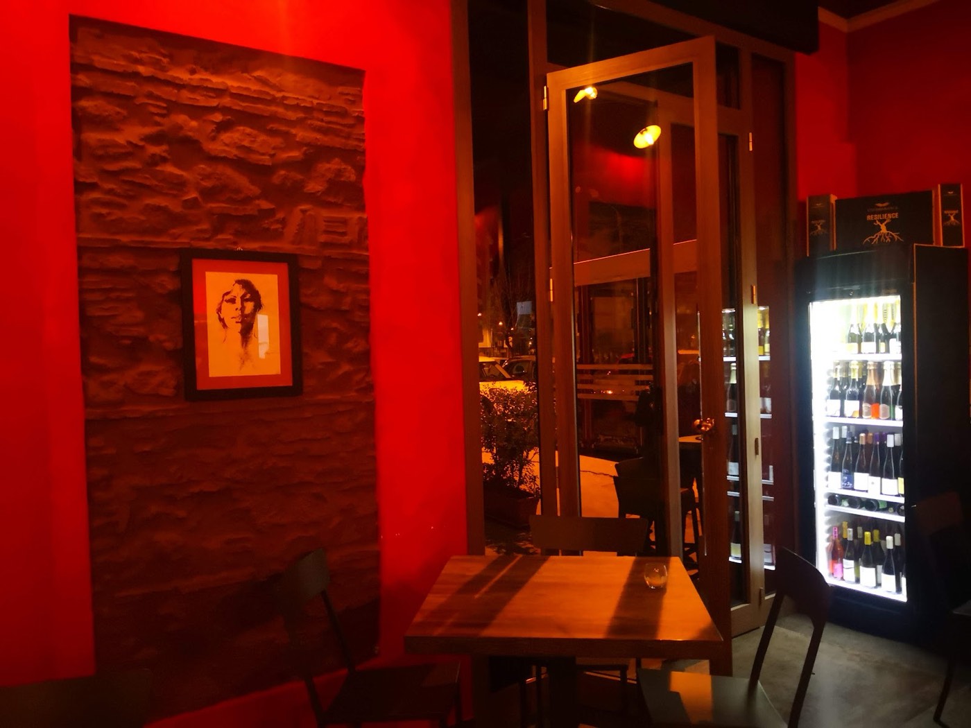 La sala di Sharaba, con le pareti color vino, il muro in pietra e la selezione di bottiglie